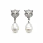 Brincos prateados com cabeças felinas e pérolas em fundo branco
