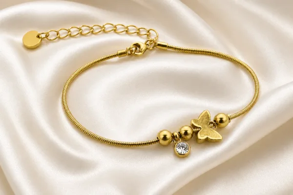 pulseira dourada com borboleta, contas e cristal em cetim marfim, referência 85383-4