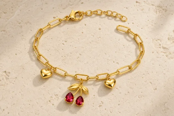 pulseira dourada com cerejas vermelhas e corações em pedra clara de tom quente, referência 85384-3