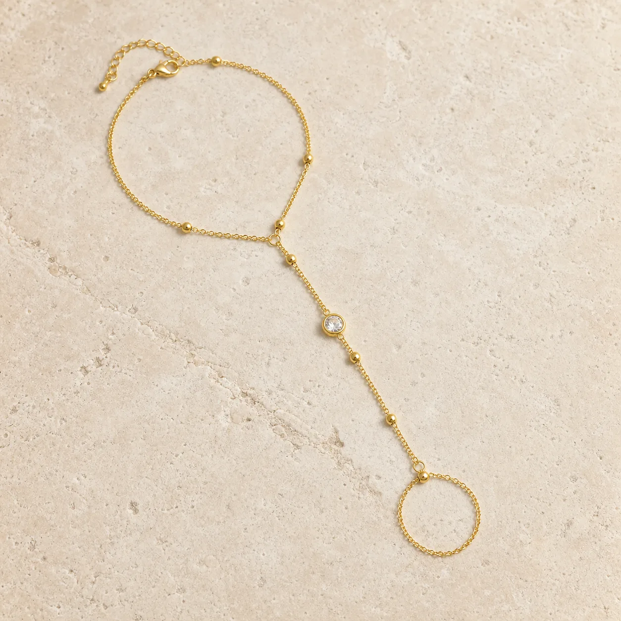 pulseira de mão dourada com cristal sobre pedra clara, referência 85384-6