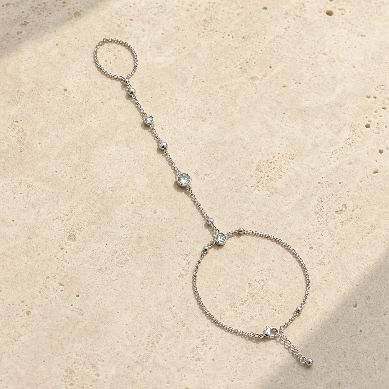 pulseira de mão prateada com cristais sobre pedra clara, referência 85391-6