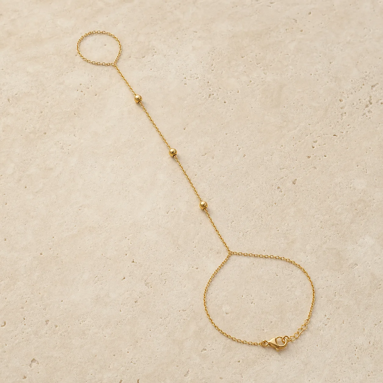pulseira de mão dourada com contas sobre pedra clara, referência 85473-2