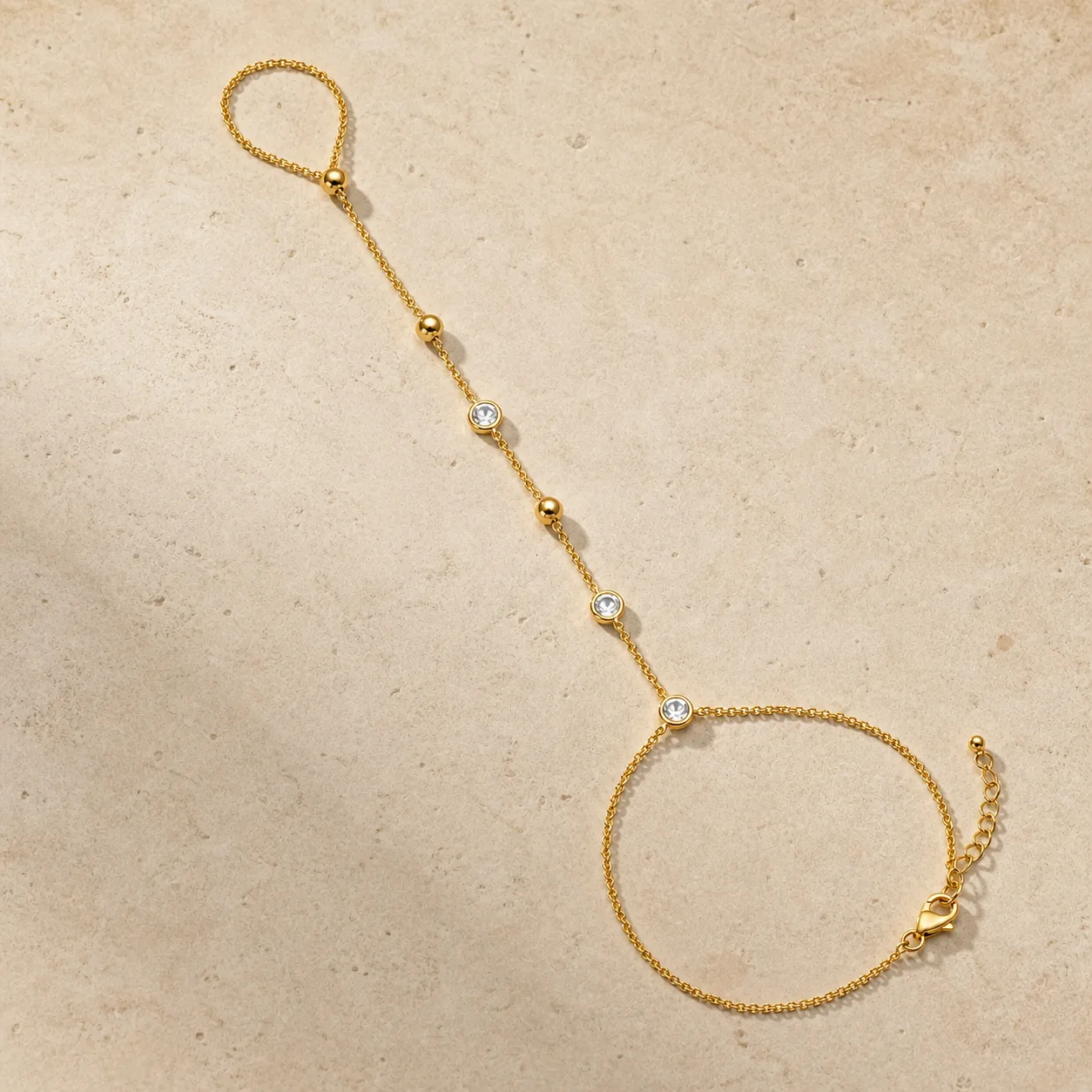 pulseira de mão dourada com cristais sobre pedra clara, referência 85474-2