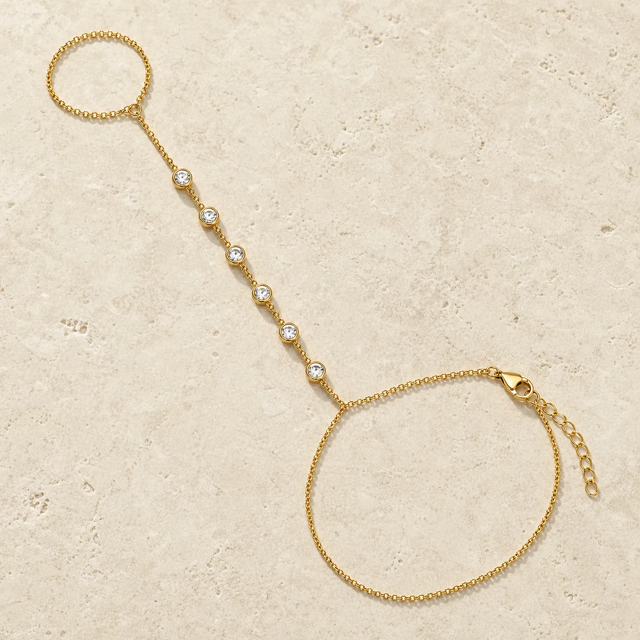 pulseira de mão dourada com seis cristais sobre pedra clara, referência 85474-3