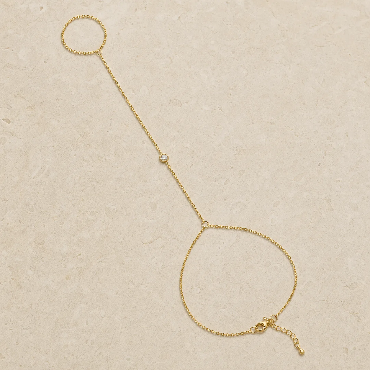 pulseira de mão dourada com cristal único sobre pedra clara, referência 85474-4