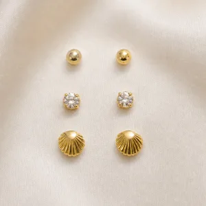 Conjunto de 3 pares de brincos dourados sobre cetim bege claro