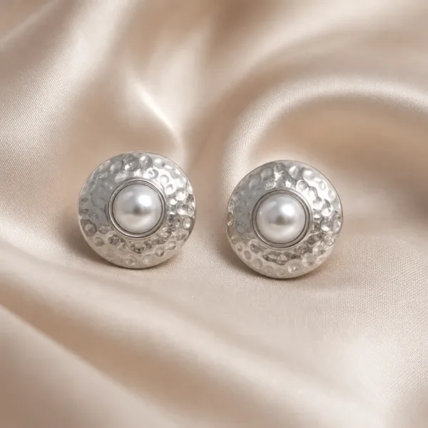 Brincos prateados martelados com pérolas sobre cetim bege claro