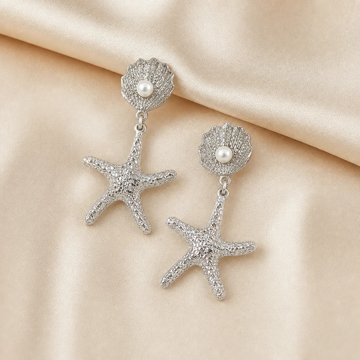 Brincos prateados de concha e estrela-do-mar 5290-S018-1B sobre cetim bege claro, conchas com p?rolas e estrelas-do-mar